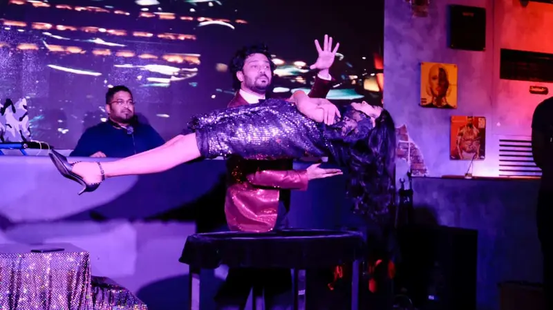 Stage magician performing a levitation illusion at an evening event
